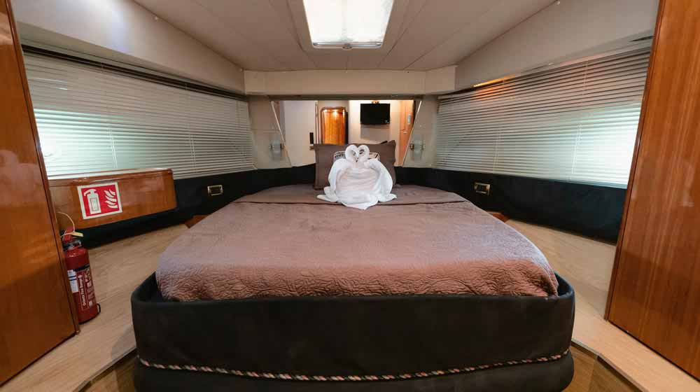 stateroom at bow of yacht with modern lightning, mirrored headboards, both sided windows
